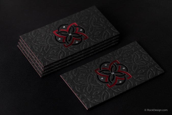 Luxury black triplex business cards featuring full-bleed debossed pattern and red and silver foil stamping.