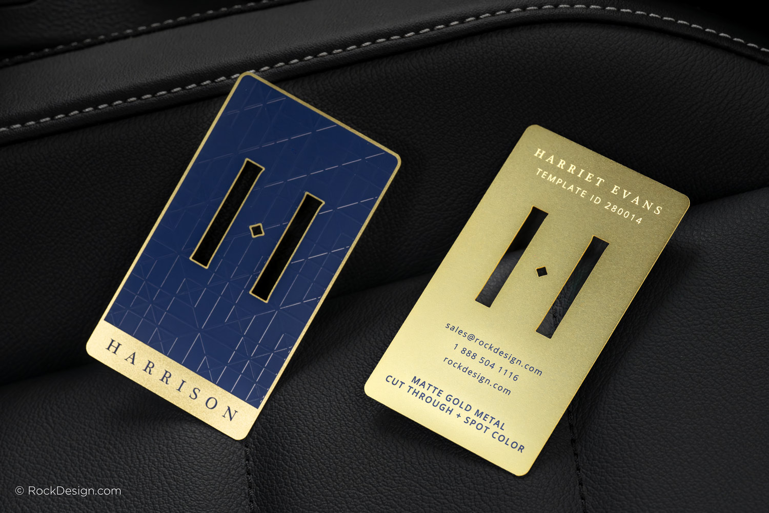 Front and back of matte gold metal business cards with navy blue spot color, cut-through logo, and premium etched details.