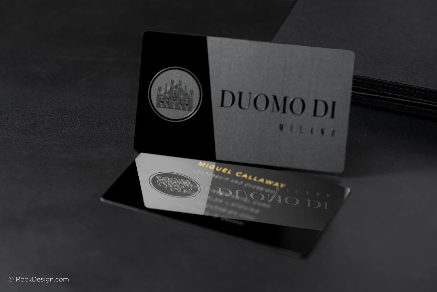 Black metal business card with etched logo and mirror finish, featuring Duomo di Milano design and gold accents for luxury branding.