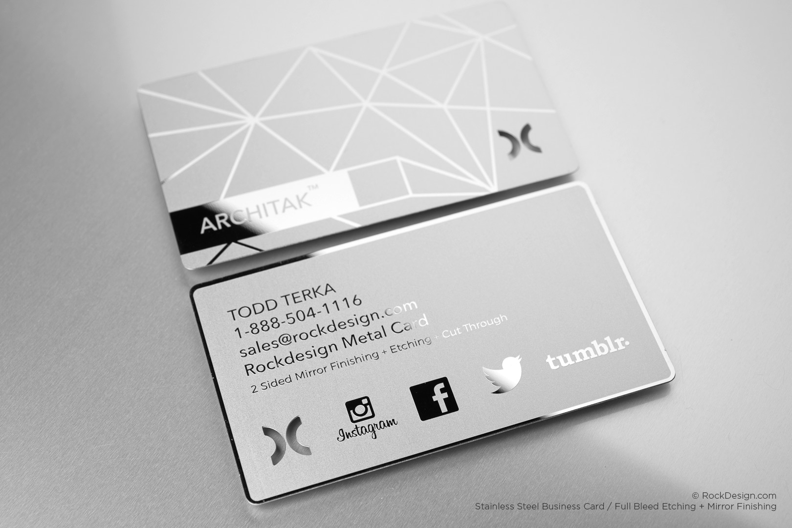 Stainless steel business cards with etched geometric design, mirror finishing, and cut-through social media icons on a sleek metallic surface.